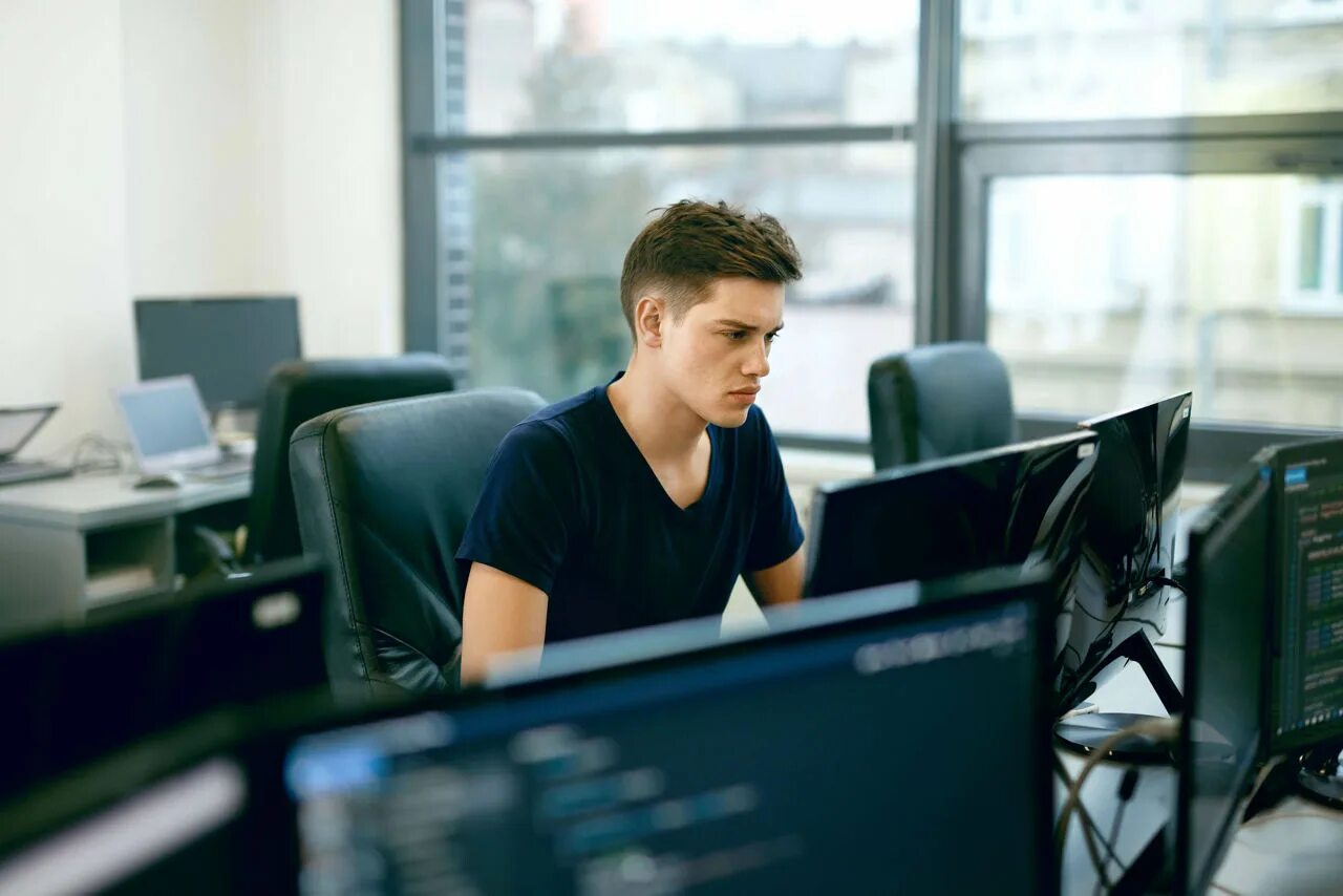 On my computer. Программист за компьютером. Крутой программист. Молодой программист. Мужчина в офисе за компьютером.