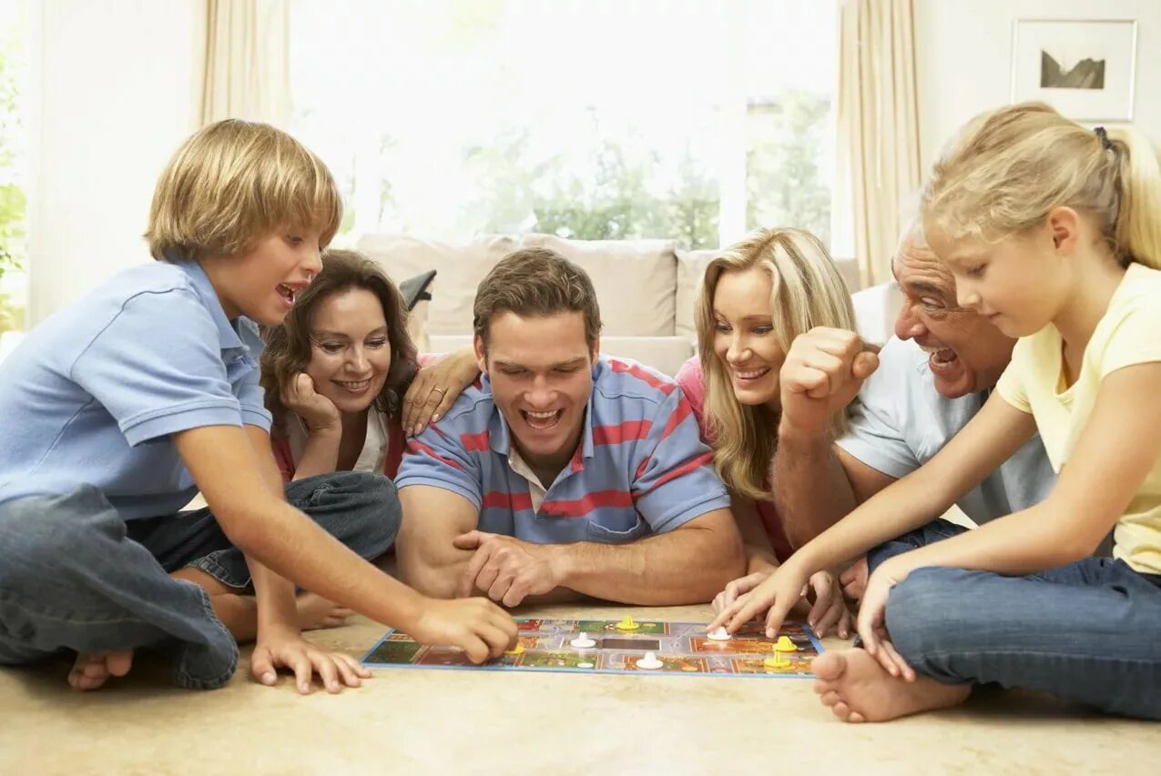 Веселое время. Общение в кругу семьи. Времяпровождение с семьей. Семья играет в настольные игры. Семья за настольной игрой.