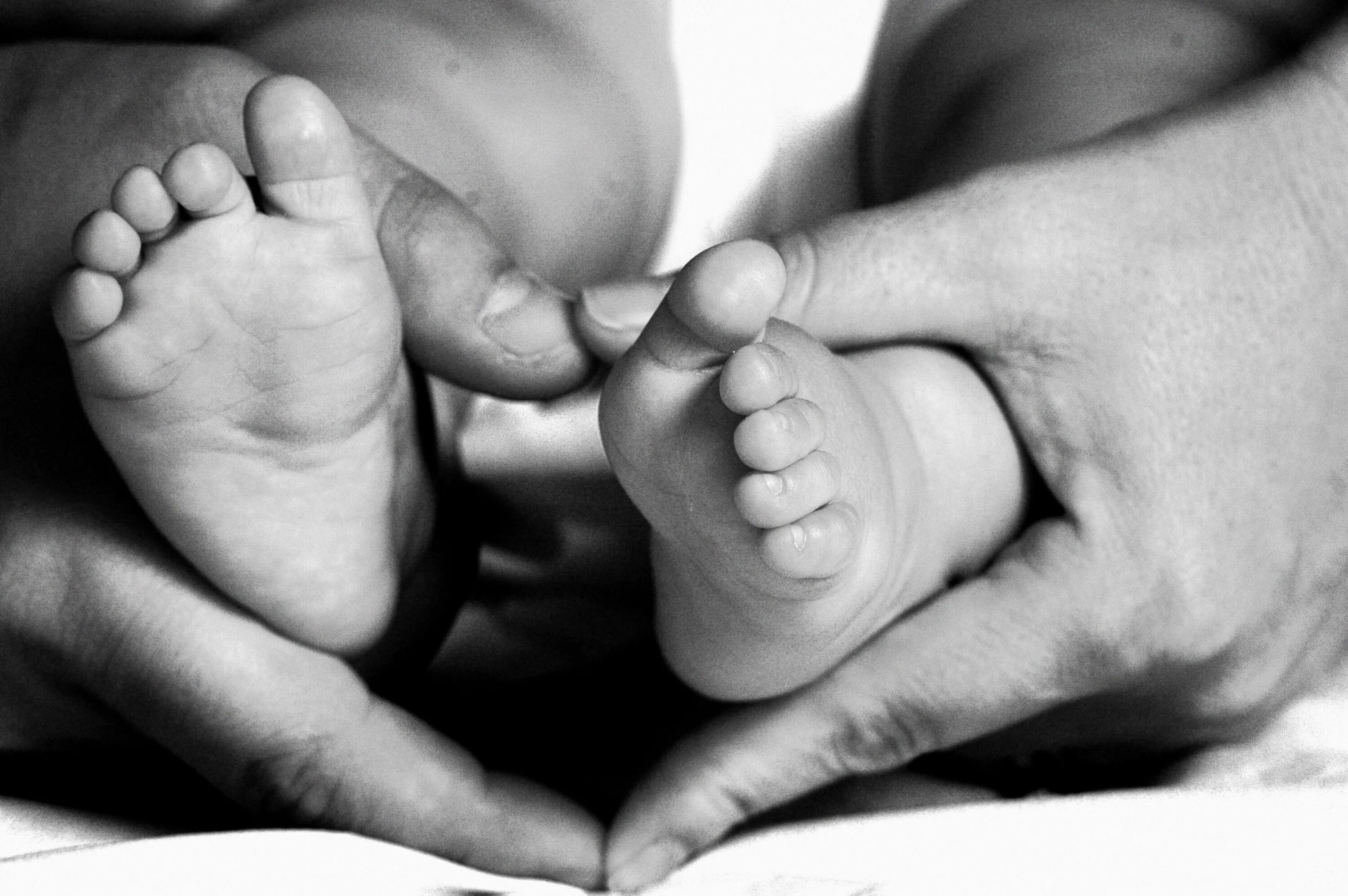 Пяточки младенца в руках. Ножки ребенка в руках родителей. Ноги младенца. Пятки новорожденного.
