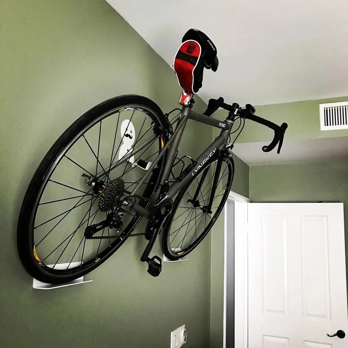 Выкаченный велосипед. Крепление для хранения велосипеда на стене. Велосипед на стене. Хранение велосипедов. Вешалка для велосипеда.