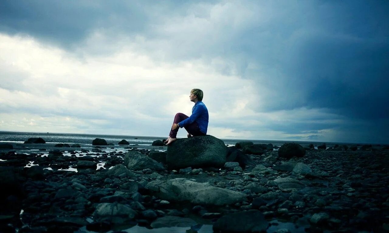 Жизнь вдали. Одинокий парень. Человек камень. Одинокое море. Человек сидит на берегу.