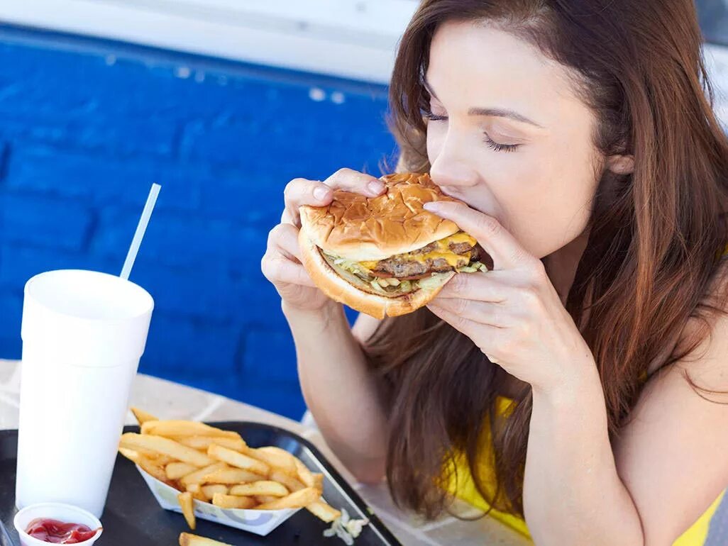 Можно ли каждый день есть фаст фуд. Человек ест бургер. Девушка ест бургер. Девушка гамбургер. Девушка ест гамбургер.