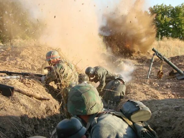 Бой кипел. Солдат в окопе под обстрелом.