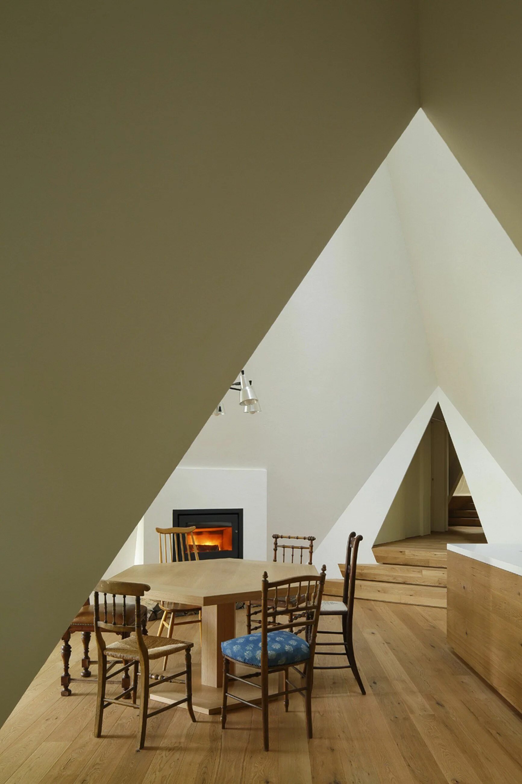 Tiny triangular loft with reading nooks and a skylight opening up to a roof deck