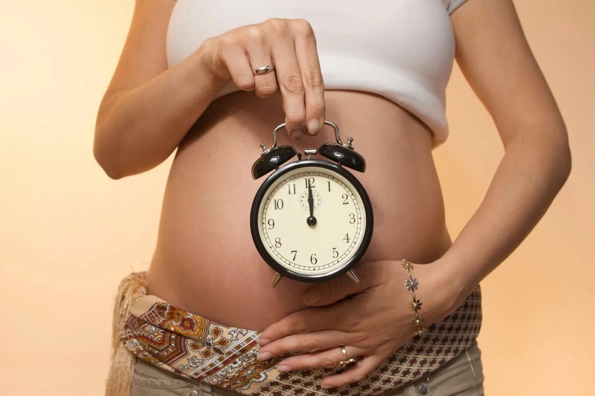 Картинки беременных женщин. Беременный живот и часы. Родить после 35