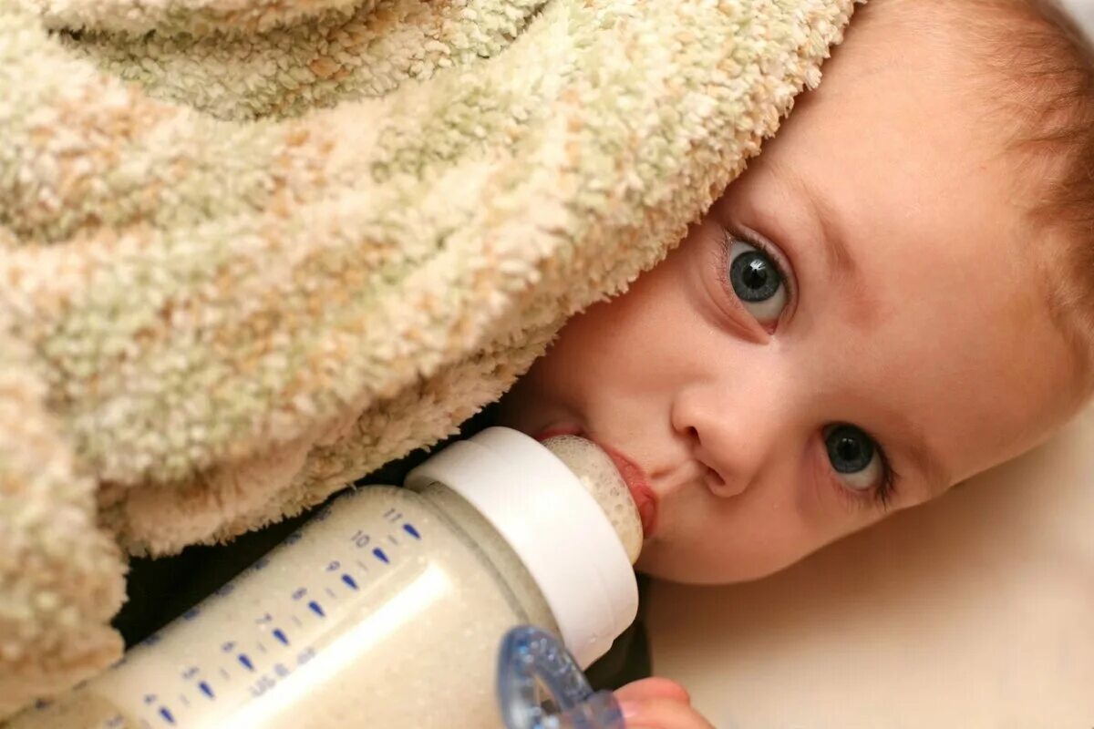 Малыш с бутылочкой. Искусственное вскармливание. Ребенок кушает из бутылочки. Малыш пьет из бутылочки.