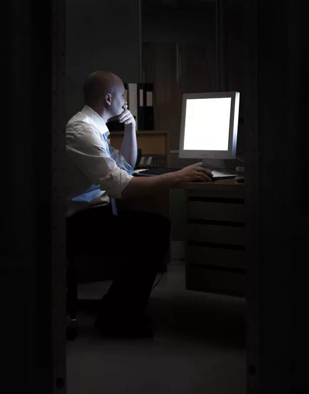 Человек в офисе за компьютером. Человек в кабинете. Люди сидят за столом в офисе. Офис ночью.