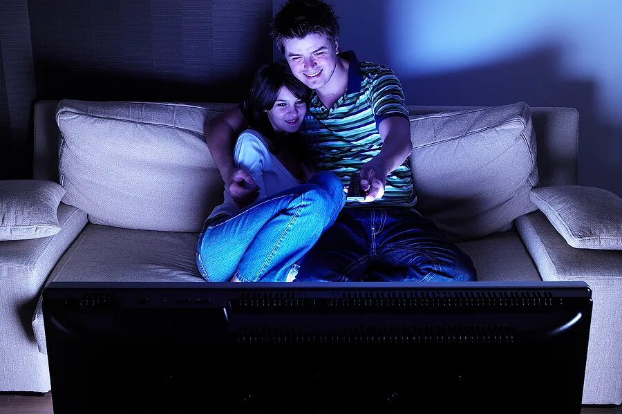 Вместе смотрят телевизор. Человек перед телевизором в темноте. Пара на диване перед телевизором. Парень с девушкой перед телевизором. Ночью перед телевизором.