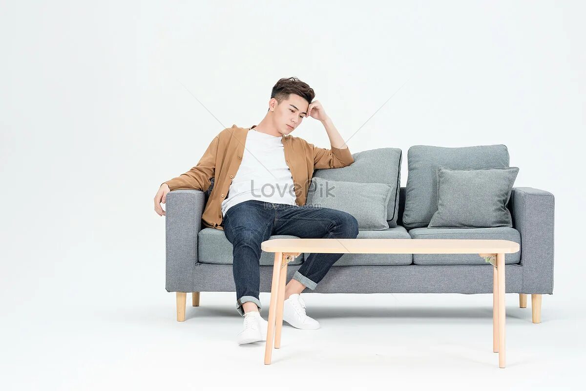 Мужчина на диване. Мужчина сидит на диване. Сидит на диване. Молодой парень сидит на диване.