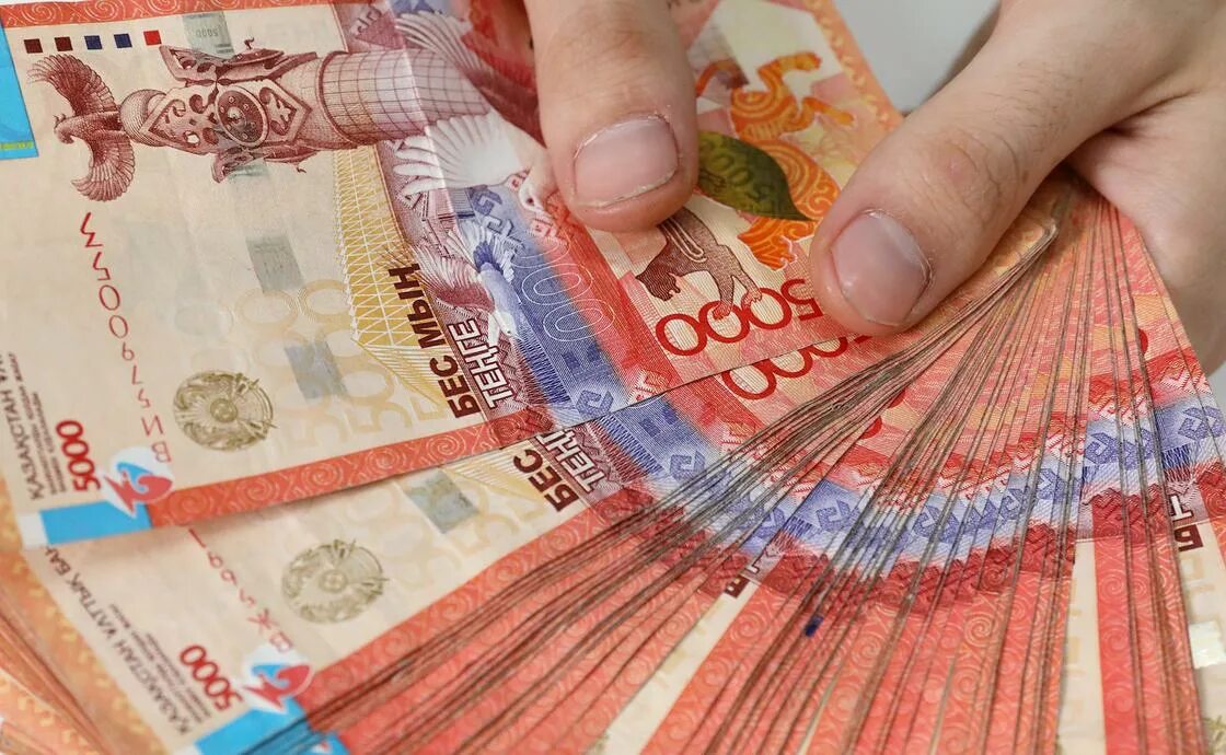 Тенге. Деньги тенге. Казахстанские деньги в руках.