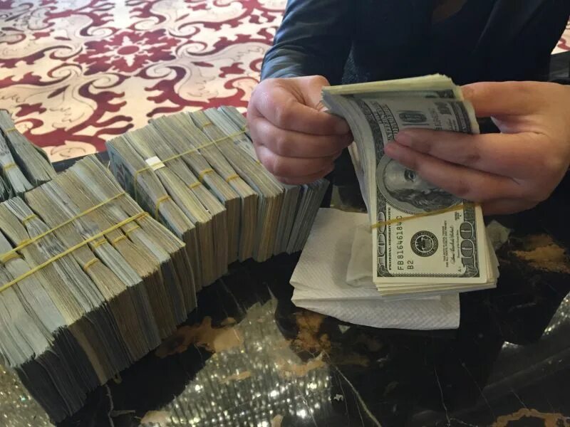 Деньги в реальном времени. Пачка долларов в руке. Деньги на столе. Пачка денег в руках. Пачка денег в руках доллары.