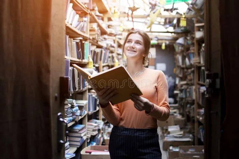 She a lot of books. Мужчина помогает женщине в библиотеке. Женщина в библиотеке открыла книгу. Мужчина, женщина в библиотеке улыбаются.