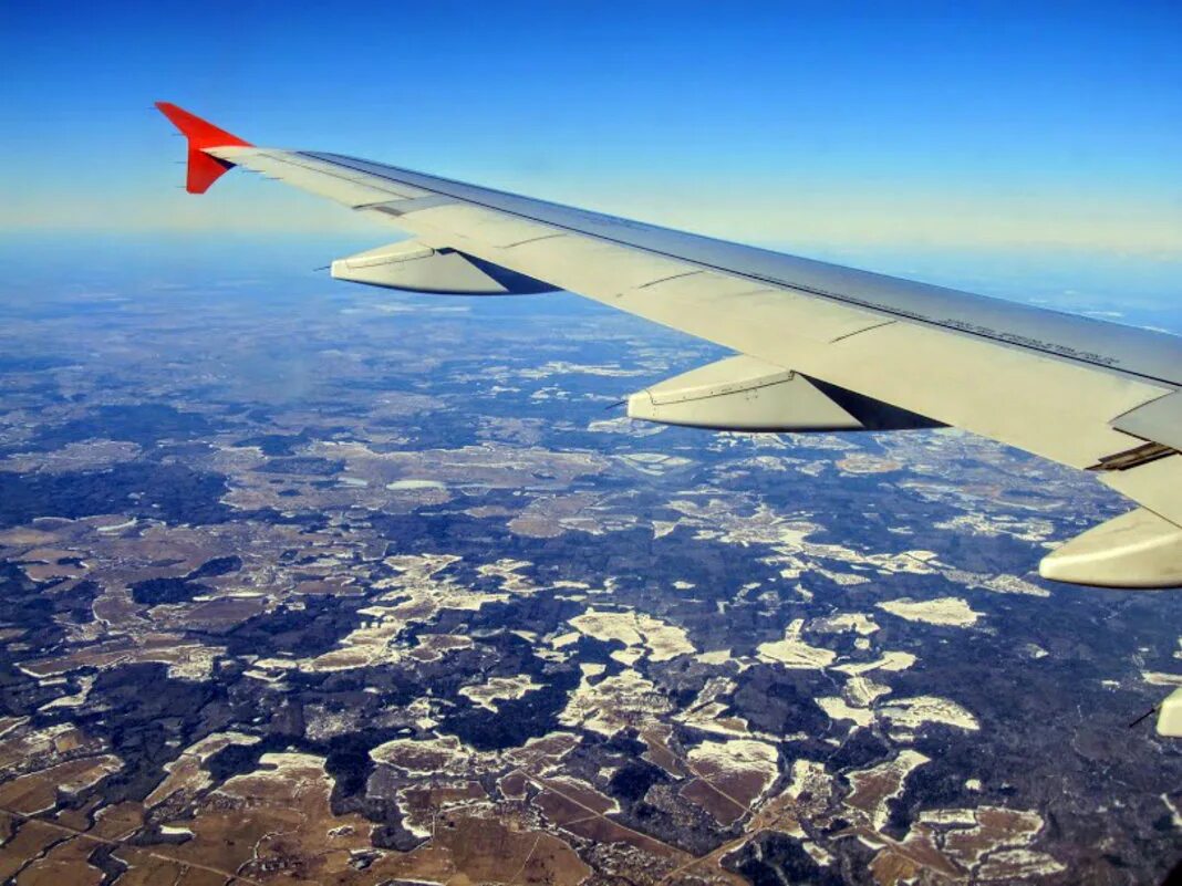 вид с самолета на землю. самолет и природа. вид из иллюминатора. под зеленым крылом самолета. крыло самолета.