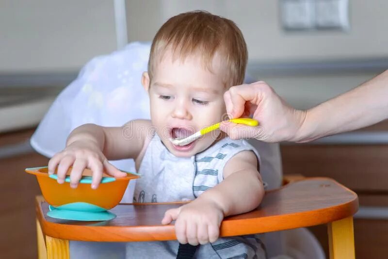 Рот сидеть видео. Маленький стульчик для кормления ребенка. Mother and Baby eat with Spoons in the Baby Chair. Малыш 11 месяцев держит ложку или кружку. Фото малыша когда его держат и кормят.