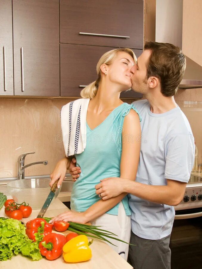 Дает мужу на кухне. Мужчина и женщина вместе на кухне. Пара обнимается на кухне. Готовим вместе. Парень обнимает на кухне.