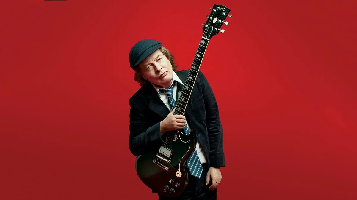 Гитарист AC DC Ангус. AC DC Angus young молодой. Соло гитарист AC DC. AC DC Angus young 2021.