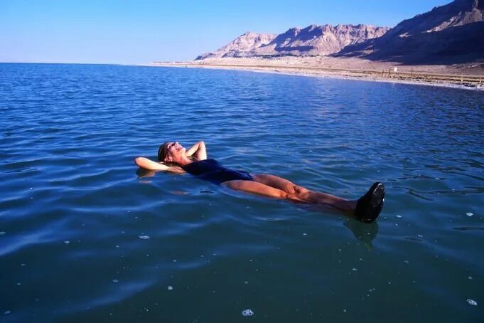 Мертвое море. Человек лежит в воде. Лежать на воде.