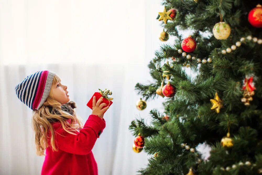 Прийти на елку. Девочка наряжает елку. Девочка у новогодней елки. Девочка возле елки. Дети около елки.