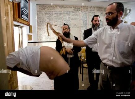 An ultra-Orthodox Jewish man lightly whips a Jewish man inside a '...