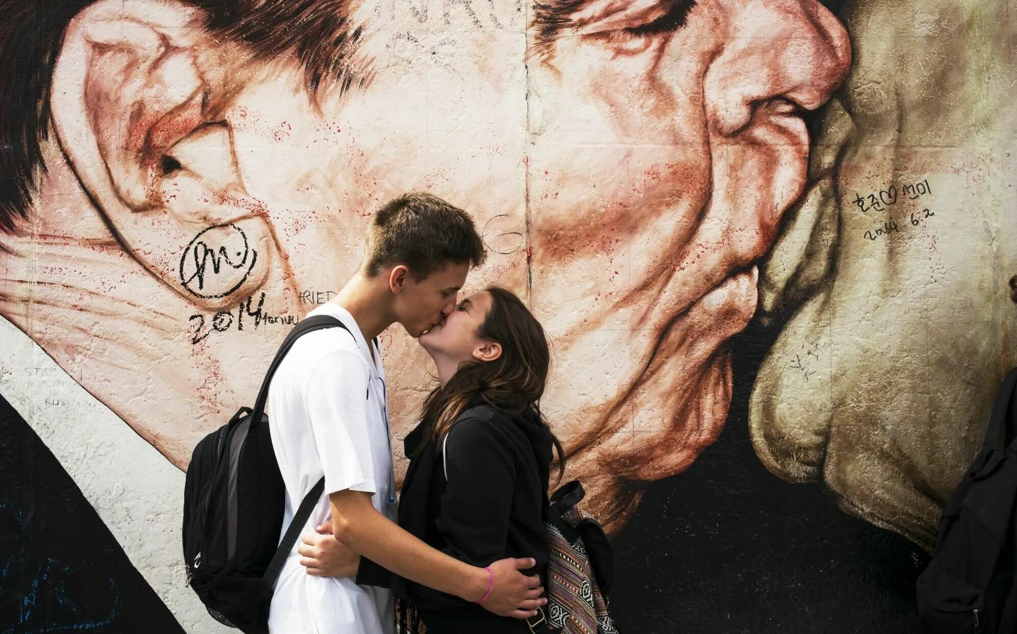 Выжить среди смертной любви. Брежнев поцелуй Берлинская стена. Поцелуй на фоне Берлинской стены. Поцелуй у стены. Берлинская стена картина.