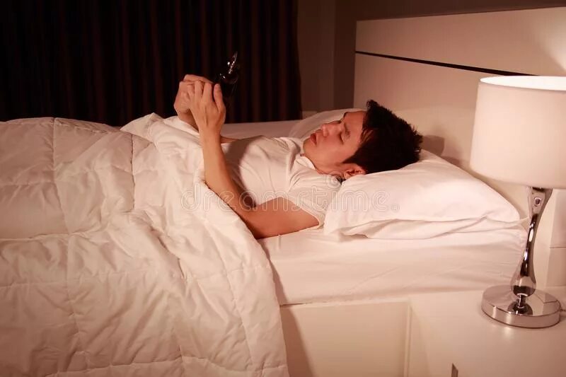 Чел лежит на кровати с телефоном. Парень с телефоном в кровати. Человек лежит на кровати. Мужчина лежит на кровати с телефоном.