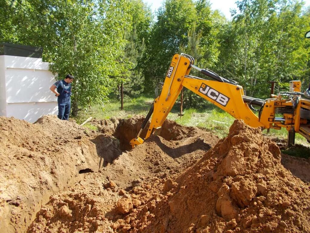 JCB копает котлован. Выемка грунта. Рытье траншеи. Копка траншей котлованов. Экскаватор роет яму