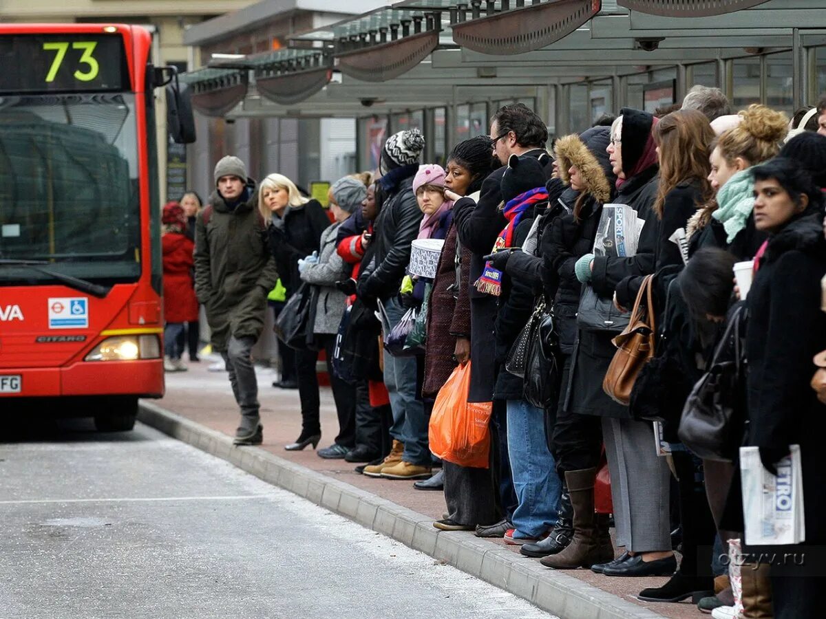 Очереди на автобус в Британии. Много людей на остановке. Люди ждут автобус. Пассажиры на остановке. Аня ждет автобус на остановке