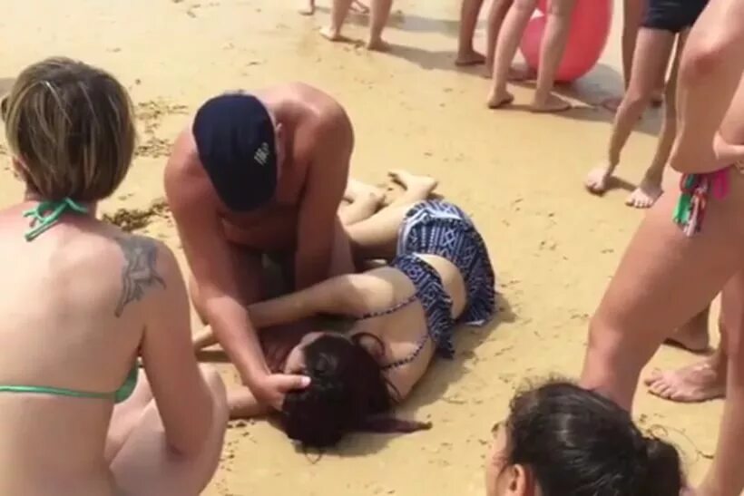 мертвая девушка в купальнике. утонувшая женщина на пляже. пляж принуждение. лежит на берегу моря. искусственное дыхание девушке на пляже.