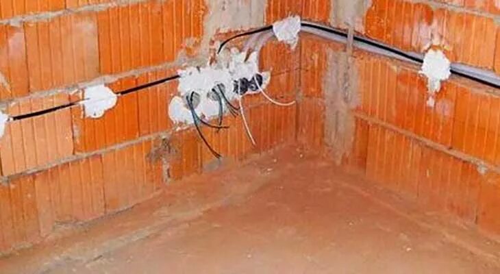 Кабель снизу. Прокладка кабеля в стене. Прокладка кабеля в штробе. Электрика в доме из керамических блоков. Проводка по низу стены в доме.