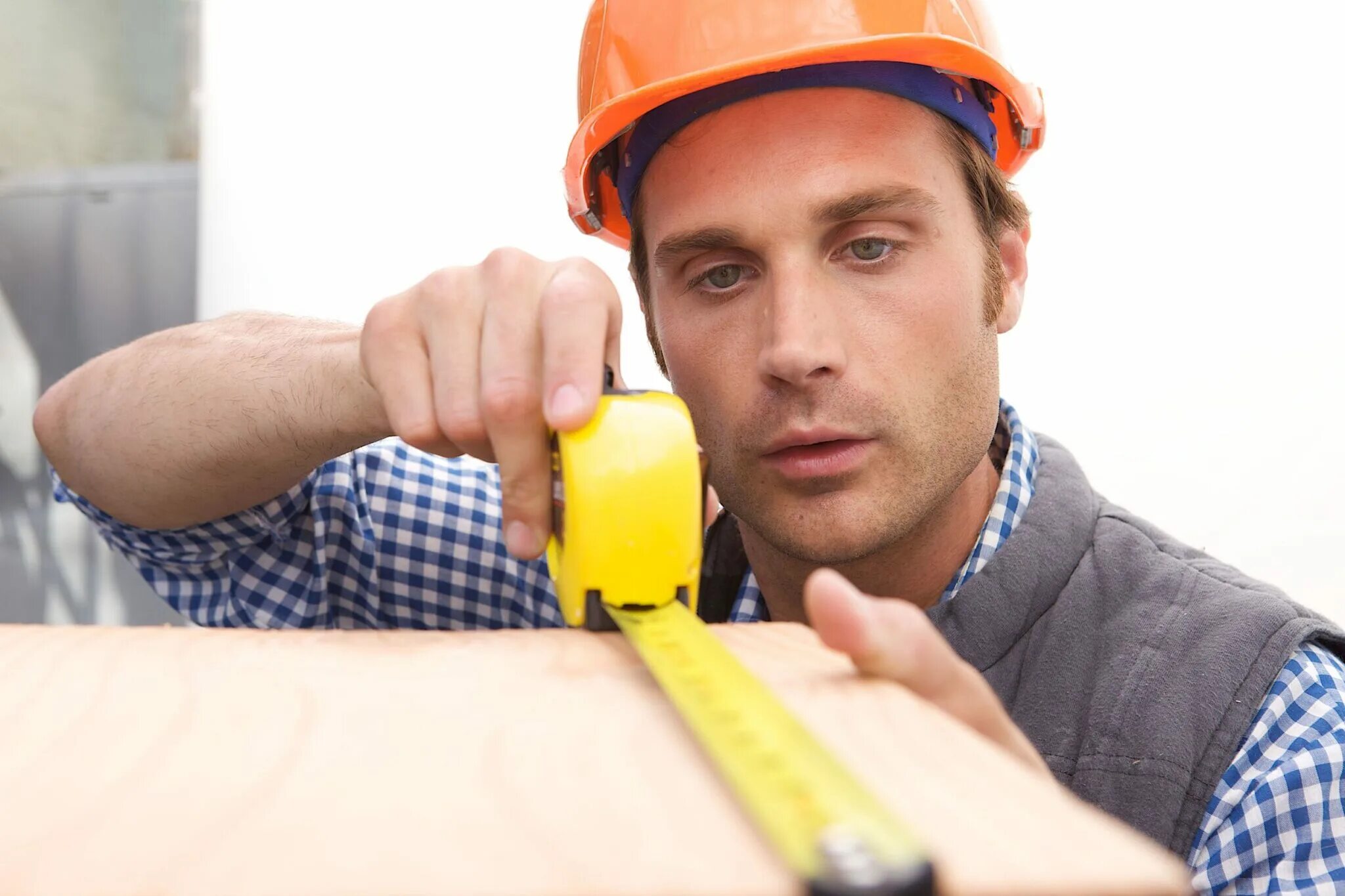 Работа рулеткой. Каска строителя. замерщик. строитель с рулеткой. мужчина строитель.