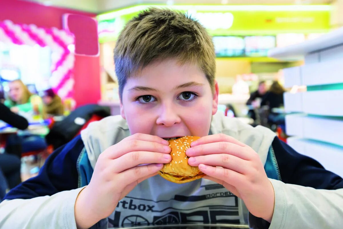 Где мальчики есть. Мальчик ест бургер. Мальчик ест гамбургер. Мальчик в кафе. Мальчик с бургером.