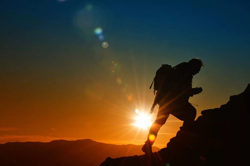 Путь испытаний. Человек поднимается в гору. Закат горы человек. Покорение вершин. Турист на закате.