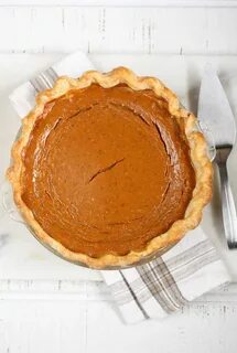 pumpkin pie on white washed wood, metal pie server to right. 