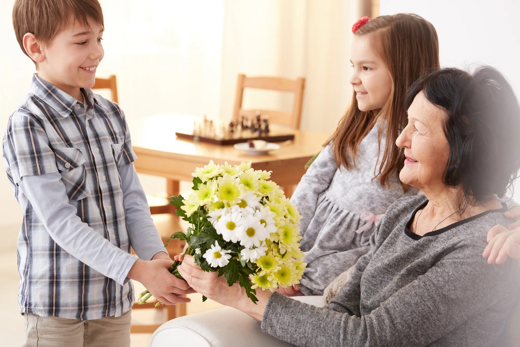 Дети поздравляют бабушек. Ребенок дарит цветы маме. Мальчик дарит цветы маме. Подарок бабушке. Цветы для бабушки.