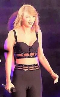 taylor swift performing on stage in black bra top and leggings with her han...