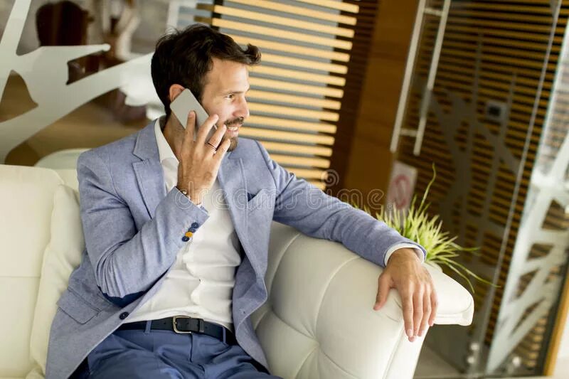 Разговор через часы. Квартира бизнесмена. Мужчина в костюме разговаривает по телефону. Мужчина в деловом костюме говорит по телефону. Бизнесмен говорит по телефону у окна.