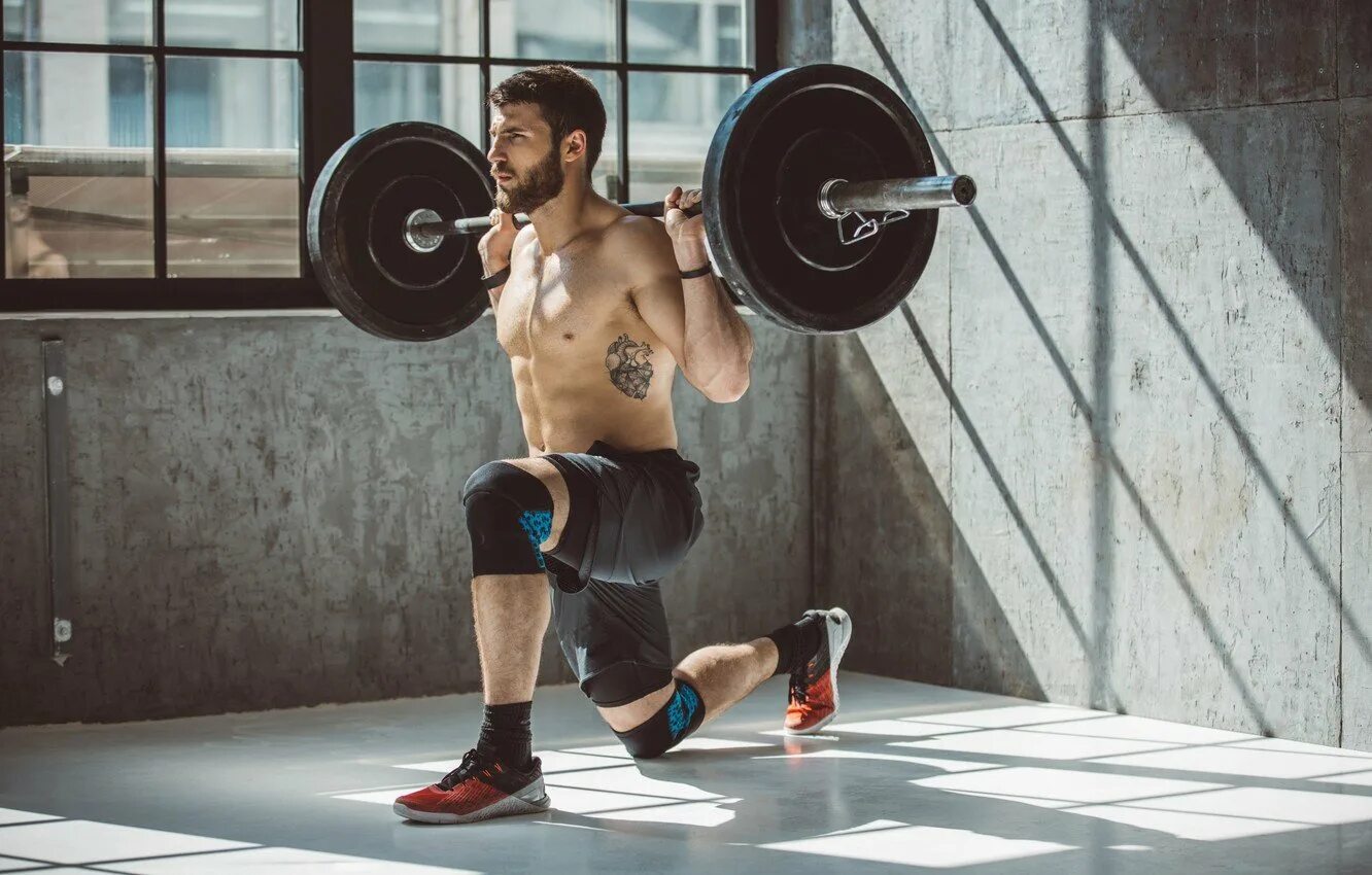 Подъем штанги на бицепс. Красивый фитнес. Спортсмены в тренажерном зале. Мужчина со штангой. Спортсмен в зале.