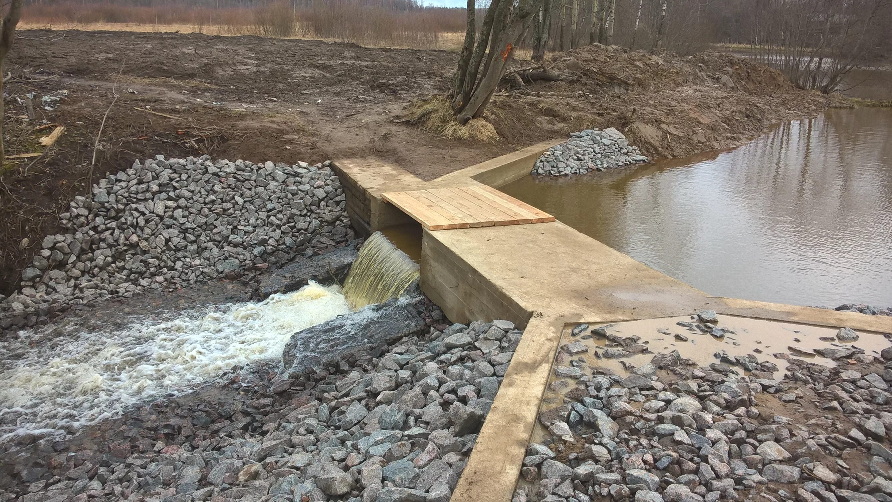 Земляная насыпная плотина. Траншейный водосброс. Земляные намывные плотины. Берегоукрепление ручья. Речка перегорожена наполненная чашка сосредоточенный