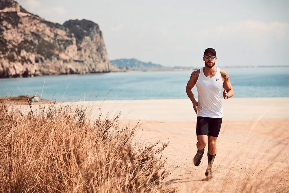 Известный двигаться. Пробежка по пляжу. Спортивный мужчина на природе. Человек бежит по песку. Пробежка вдоль моря.