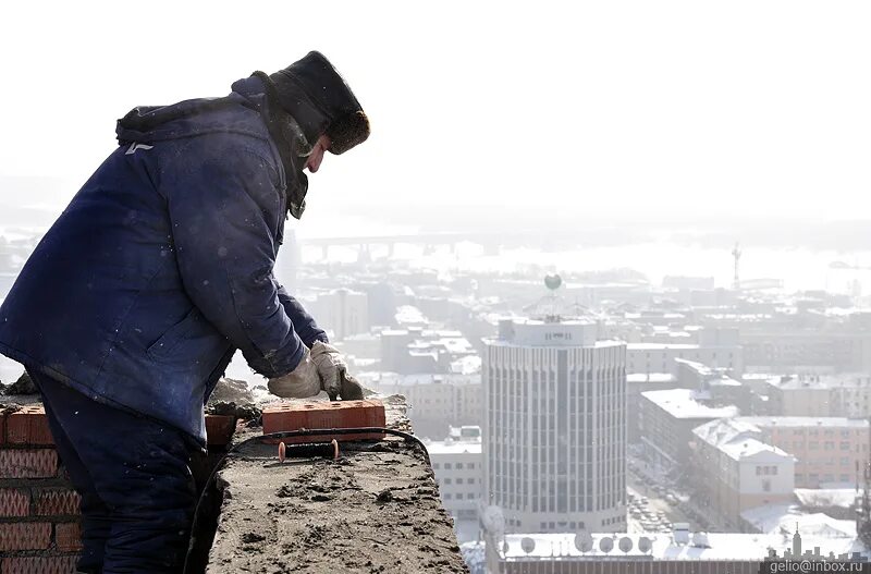 уборка снега с крыш. строитель зимой на стройке. стройка. стройка зима. зимняя стройка.