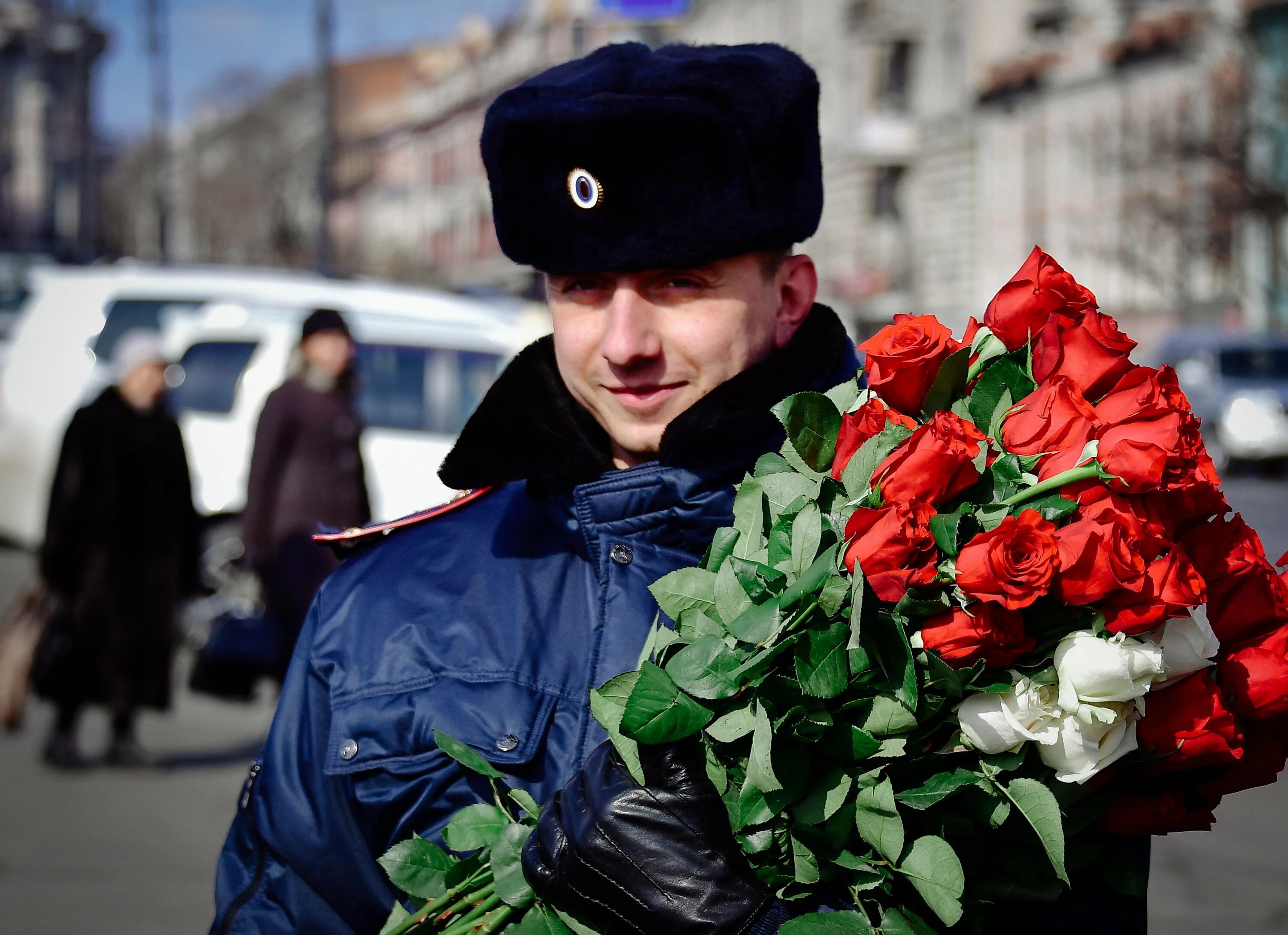 Полиция с цветами. Красивый полицейский с подарком. Полицейский с подарком в руках. Дарят работникам цветы. Полиция подарки