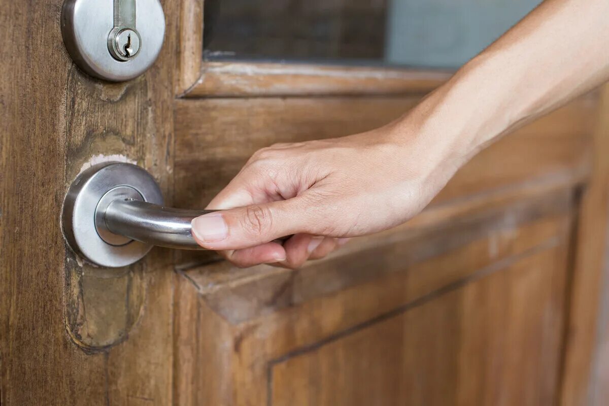 Девушка и закрытая дверь. Дверная ручка открытая. Рука открывает дверь. Девушка держит двери. Страх замкнутого пространства.