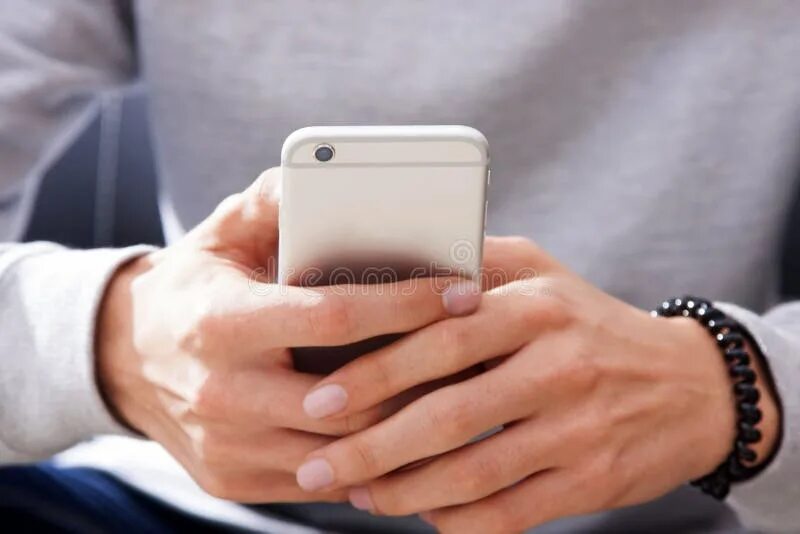 Парень с телефоном в руке. Телефон в двух руках. Два телефона. Телефон в двух руках. Рука держит смартфон.