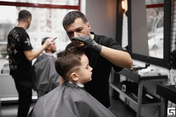 Подстригала отца. Прически в парикмахерской для мальчиков. Детские прически барбершоп. Стрижки в барбершопе для мальчиков. Парикмахер мальчик.
