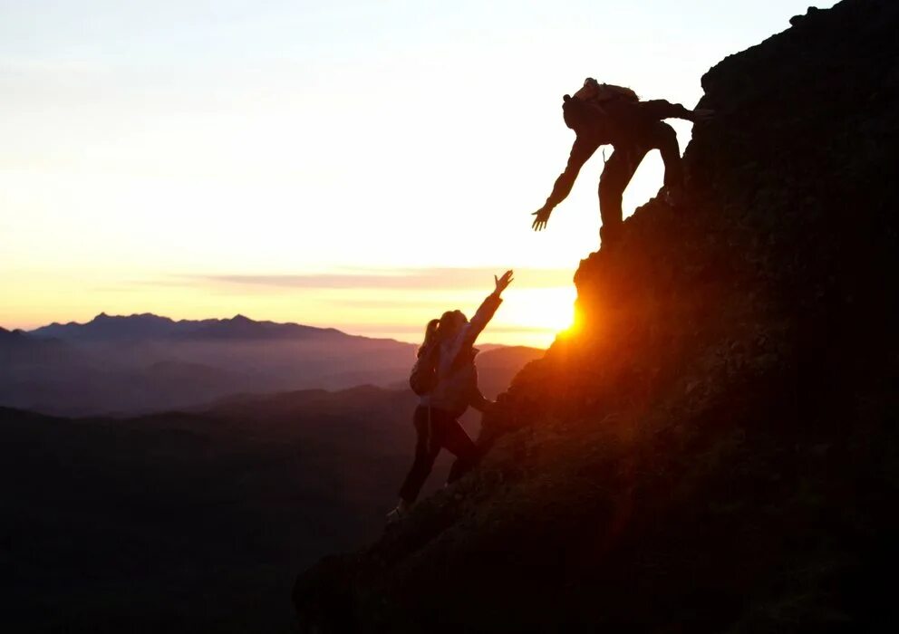 Дать помощь в горе. Человек в горах. Помогает подняться в гору. Поддержка в горах. Друзья поднимаются в гору.