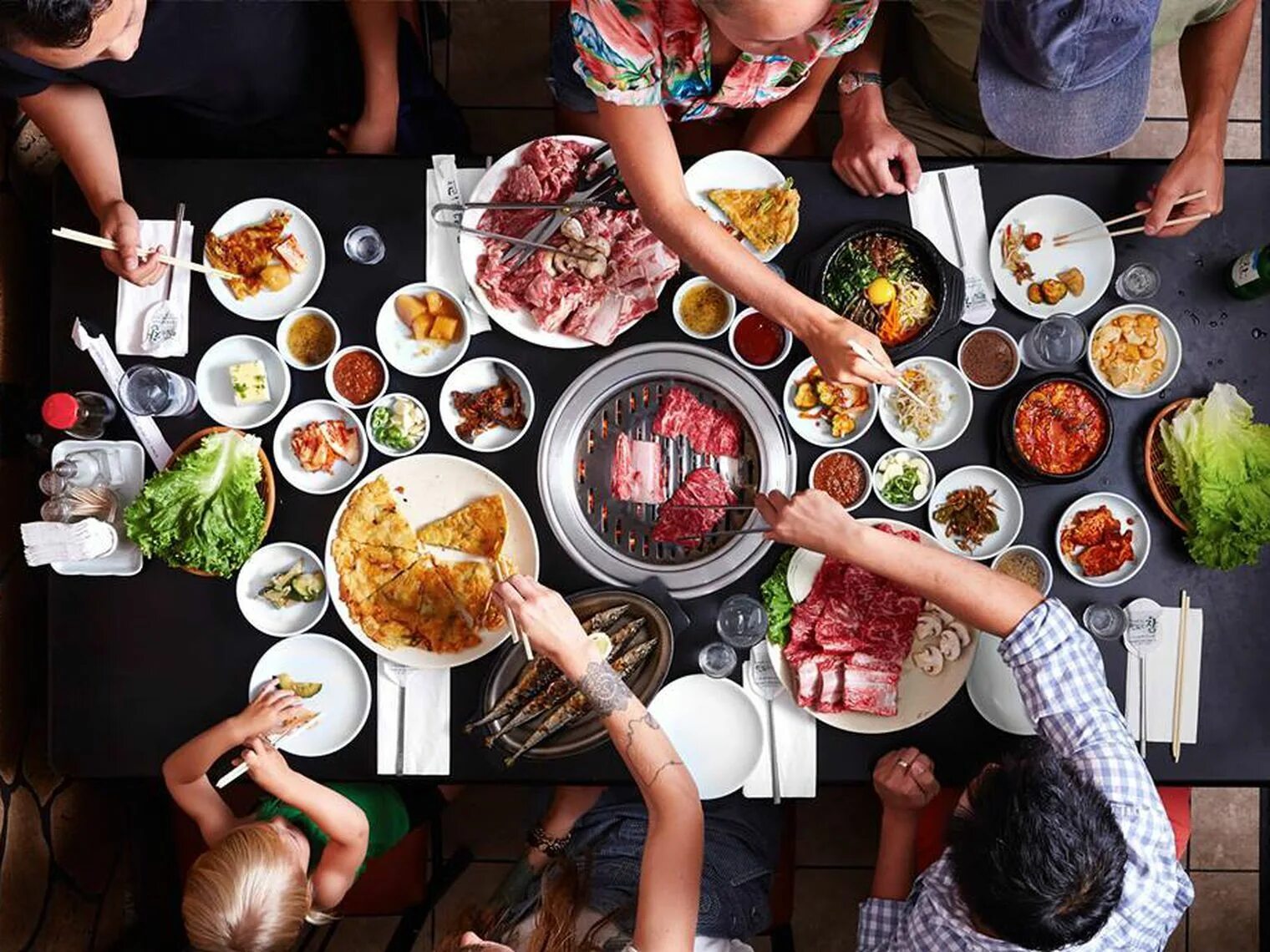 Пробуем разную еду. Корейская Трапеза. Корейская еда в ресторане. Корейский стол с едой. Стол с едой и людьми.