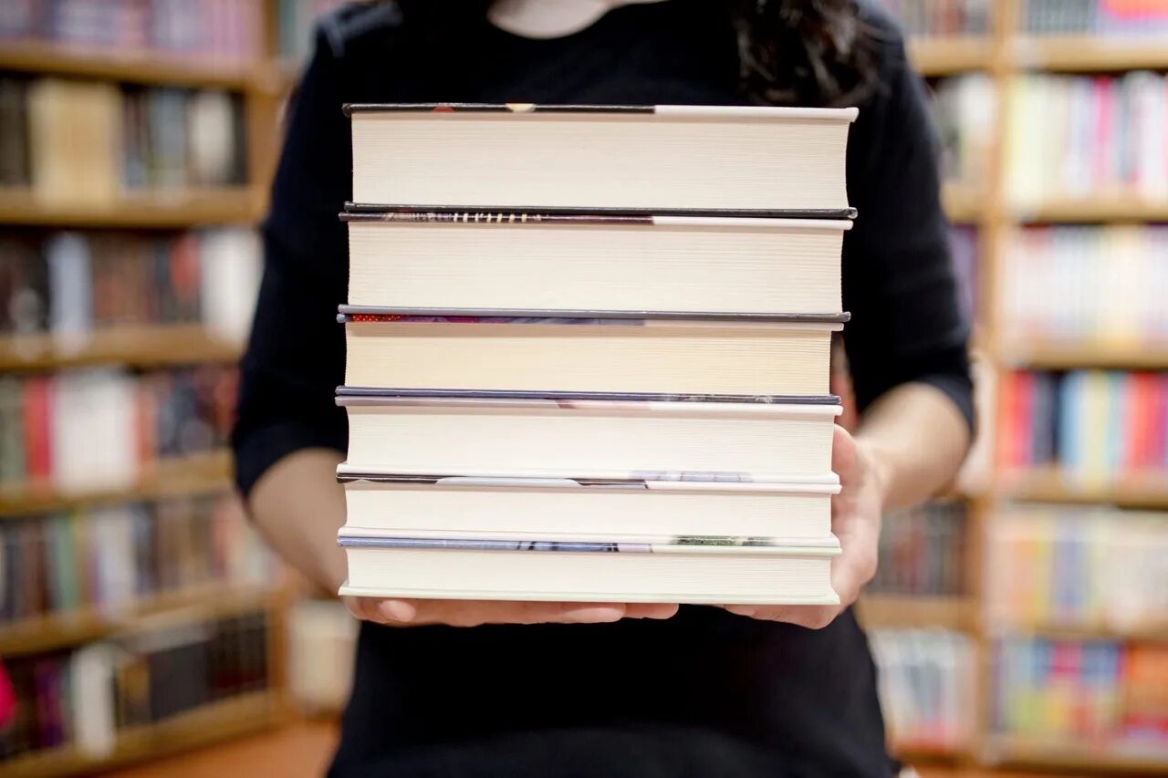 Стопка книг. Стопка книг в руках. Человек со стопкой книг. Несет стопку книг.