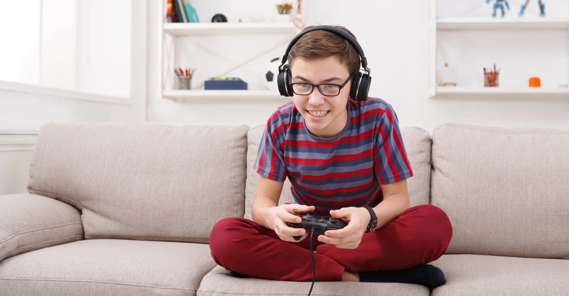 He enjoy playing. Мальчик с джойстиком. Сидит с джойстиком. Мальчик на диване с джойстиком. Подростки играющие в компьютерные игры.