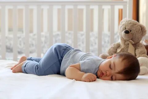 Funny baby sleeping on his stomach on bed at home. 