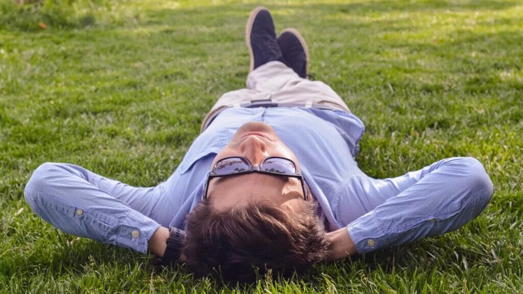 Расслабленный форум. Лечь на землю. Человек лежит на траве руки за головой. Человек релаксирует. Lie down.